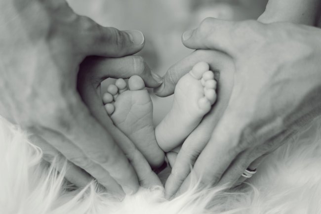 pieds de bébé entourés par les mains de ses parents