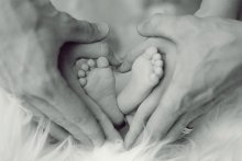 pieds de bébé entourés par les mains de ses parents